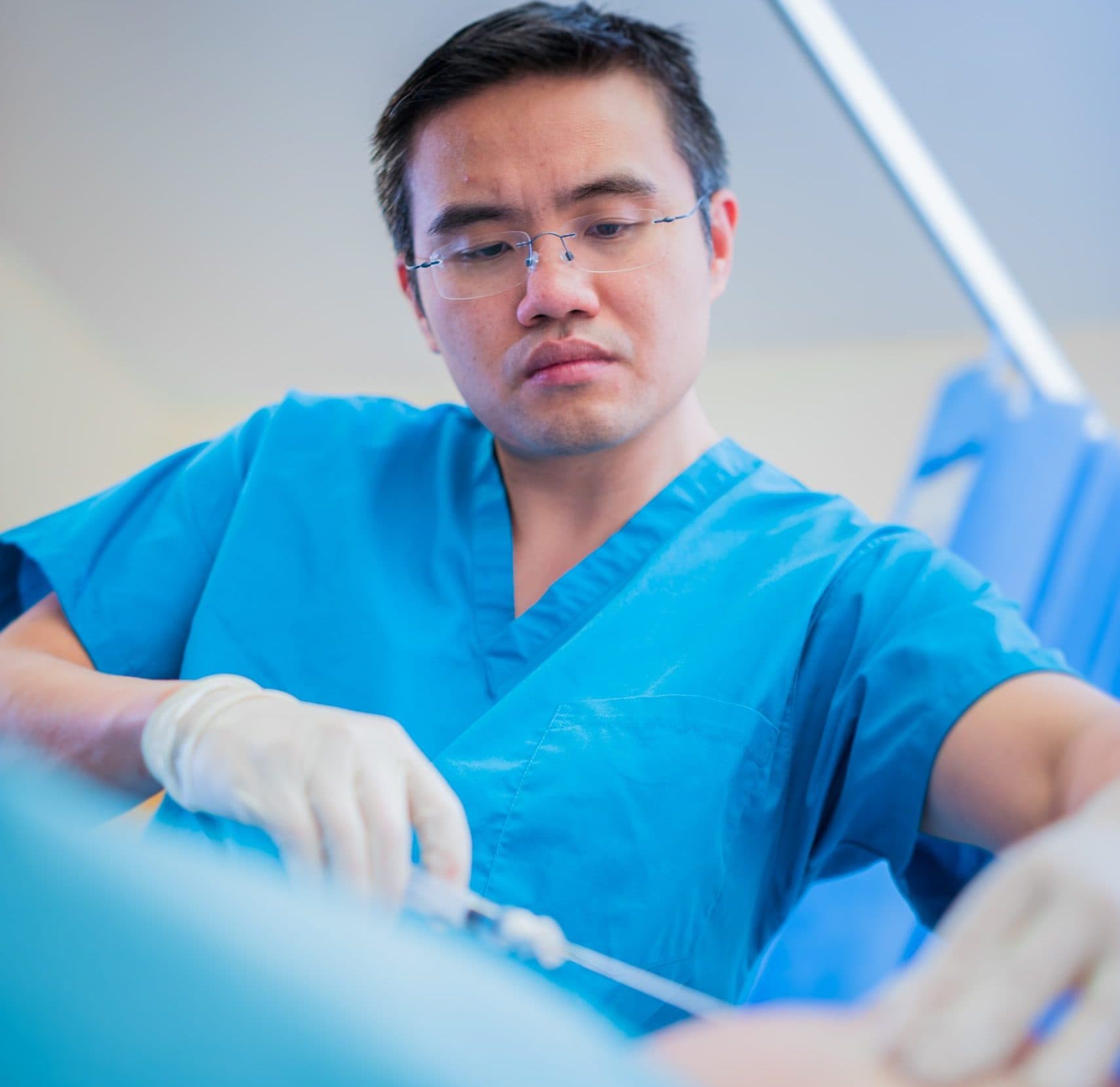 Focused doctor in blue scrubs during procedure